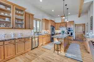 Kitchen with appliances with stainless steel finishes, a kitchen bar, decorative backsplash, a kitchen island, and light wood-style floors