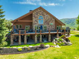 Rear view of house featuring a patio area, a deck with mountain view, and a yard
