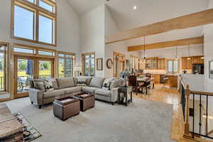 Living room featuring high vaulted ceiling, light wood-style flooring, a chandelier, and french doors