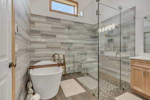 Bathroom featuring vanity, a freestanding tub, and a stall shower