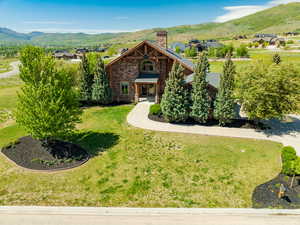 View of front of property with stone siding, a chimney, a mountain view, and a front yard
