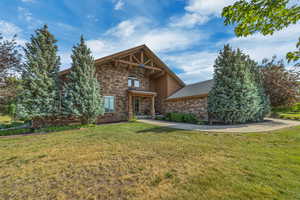View of front of property featuring stone siding and a front lawn