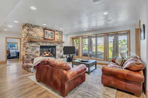 Living room with a fireplace, wood finished floors, recessed lighting, and a textured ceiling