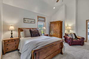 Bedroom with light colored carpet, high vaulted ceiling, and a ceiling fan