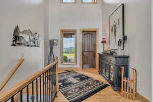 Foyer with wood finished floors and a high ceiling