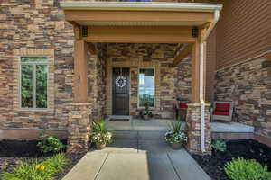 Doorway to property featuring stone siding and a porch