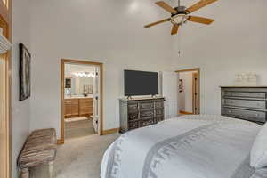 Bedroom featuring a high ceiling, light carpet, connected bathroom, and ceiling fan