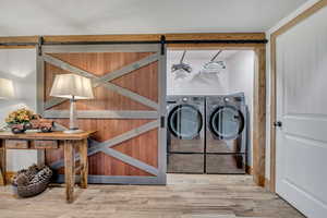 Washroom featuring a barn door, washing machine and clothes dryer, and wood finished floors