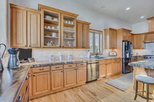 Kitchen with stainless steel dishwasher, black refrigerator, light wood-style floors, backsplash, and recessed lighting