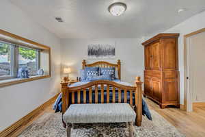 Bedroom with light wood-style floors and a textured ceiling