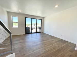 Empty room featuring plenty of natural light, wood finished floors, recessed lighting, and stairs
