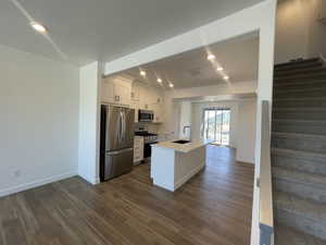 Kitchen featuring appliances with stainless steel finishes, dark wood-type flooring, white cabinets, recessed lighting, and backsplash