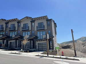 View of front of house with a mountain view, stone siding, board and batten siding, an attached garage, and driveway
