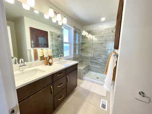 Bathroom with tile patterned flooring, a shower stall, and double vanity