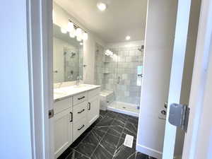 Bathroom with a shower stall, double vanity, marble look tiles, and recessed lighting