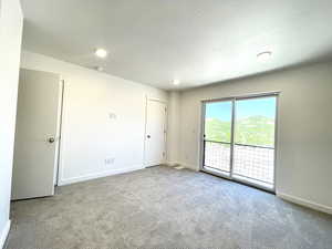 Carpeted empty room with a textured ceiling and recessed lighting