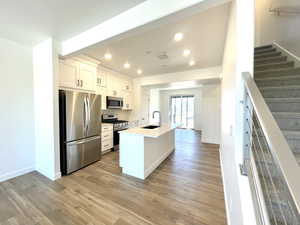 Kitchen with stainless steel appliances, recessed lighting, light wood-style flooring, white cabinetry, and decorative backsplash