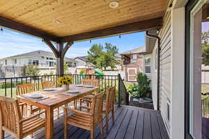 Deck featuring a playground, a shed, a residential view, outdoor dining area, and a fenced backyard