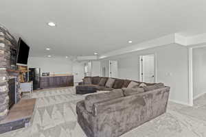 Living room with light colored carpet, a fireplace, recessed lighting, and a textured ceiling