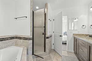 Ensuite bathroom featuring vanity, a stall shower, a bath, tile patterned flooring, and recessed lighting