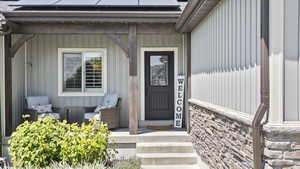 Property entrance featuring roof mounted solar panels and stone siding