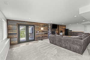 Living room with wood walls, recessed lighting, a brick fireplace, french doors, and light tile patterned flooring