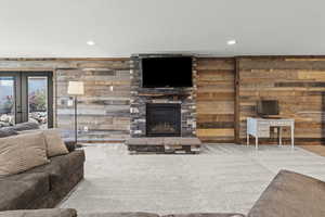 Living area with wood walls, recessed lighting, carpet flooring, a fireplace, and a textured ceiling