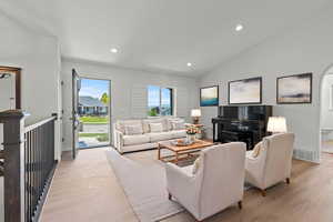 Living area featuring light wood finished floors, recessed lighting, and vaulted ceilingPhoto virtually staged