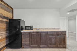 Kitchen featuring black appliances, dark brown cabinets, light countertops, and light colored carpet