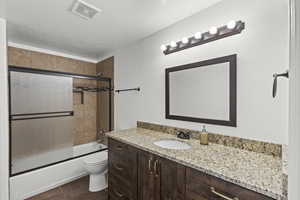 Full bathroom with vanity, a textured ceiling, enclosed tub / shower combo, and tile patterned floors