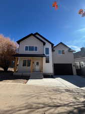View of front of home with a porch, driveway, and a garage