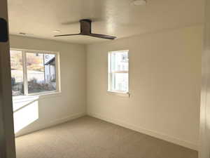 Carpeted empty room featuring a textured ceiling and ceiling fan