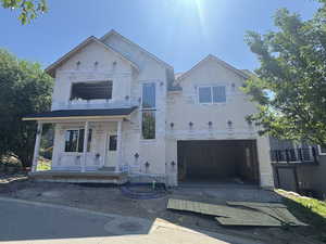 Property in mid-construction with dirt driveway, an attached garage, and covered porch