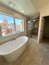 Full bath with a soaking tub, a stall shower, a textured ceiling, recessed lighting, and a spacious closet