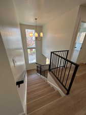 Staircase featuring wood finished floors, a chandelier, and a textured ceiling