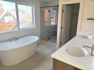 Full bath featuring double vanity, a soaking tub, a shower stall, and light tile patterned floors