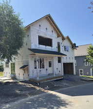 Unfinished property featuring a garage, covered porch, and dirt driveway