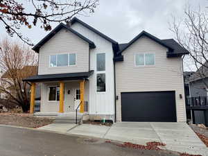 View of front of house with board and batten siding, a porch, concrete driveway, a garage, and a shingled roof