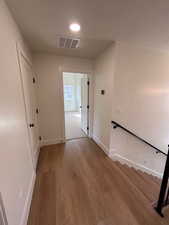 Hall featuring light wood finished floors, a textured ceiling, and stairs