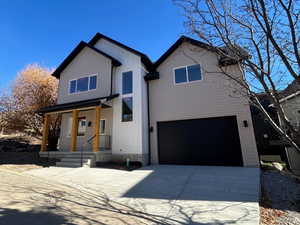 View of front of home with a porch, driveway, a garage, and board and batten siding