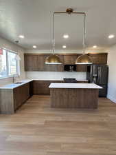 Kitchen with decorative light fixtures, black appliances, backsplash, a center island, and a textured ceiling