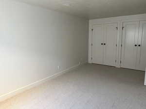 Unfurnished bedroom featuring carpet, two closets, and a textured ceiling