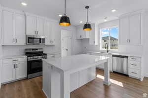 Kitchen featuring appliances with stainless steel finishes, decorative backsplash, white cabinets, wood finished floors, and recessed lighting