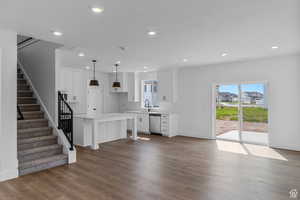Kitchen featuring dishwasher, light countertops, white cabinetry, wood finished floors, and recessed lighting