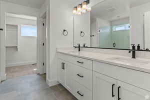 Full bathroom with double vanity, healthy amount of natural light, and a shower stall