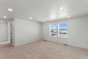Empty room featuring light carpet, recessed lighting, and a textured ceiling