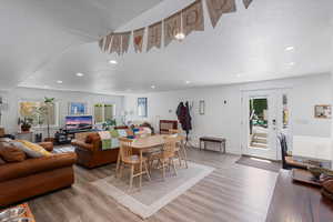 Dining room with a textured ceiling, light wood-style flooring, recessed lighting, and plenty of natural light