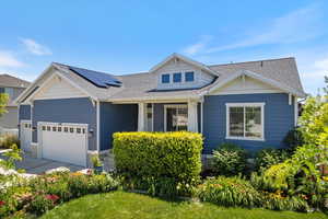 View of front facade with a shingled roof, solar panels, and a garage