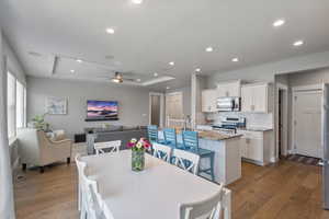 Dining space featuring light wood-style floors, ceiling fan, a raised ceiling, and recessed lighting
