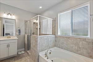 Bathroom featuring a garden tub, vanity, a shower stall, and plenty of natural light